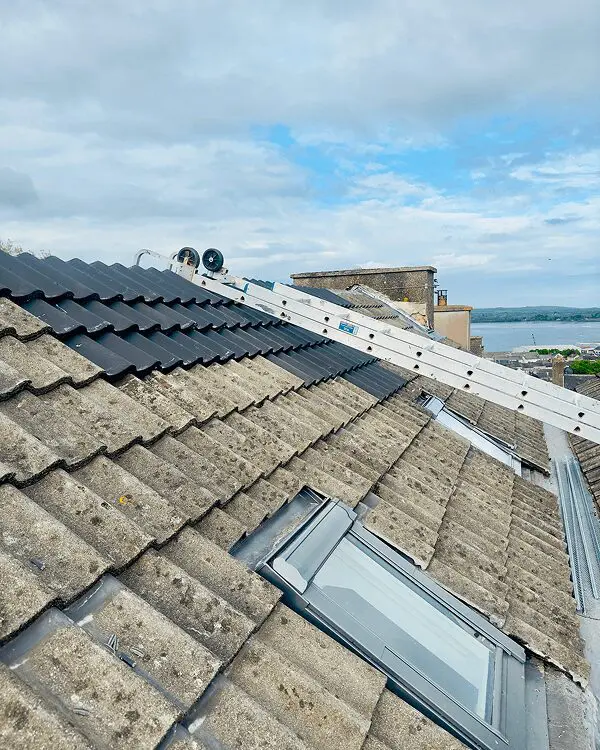 Rooftop with ladder and cloudy sky view.