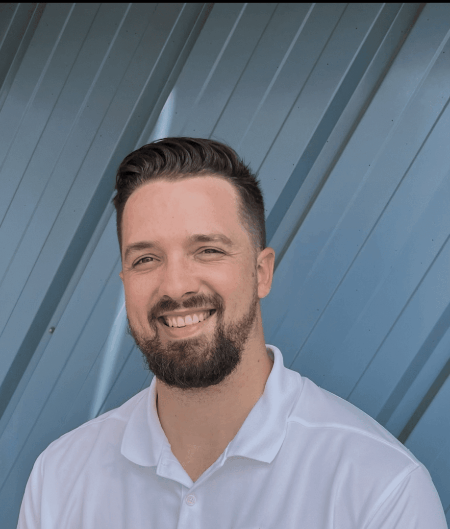 Smiling man with beard in white shirt against a geometric blue background.