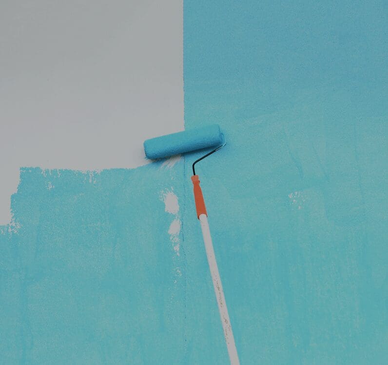Blue paint roller painting a wall.
