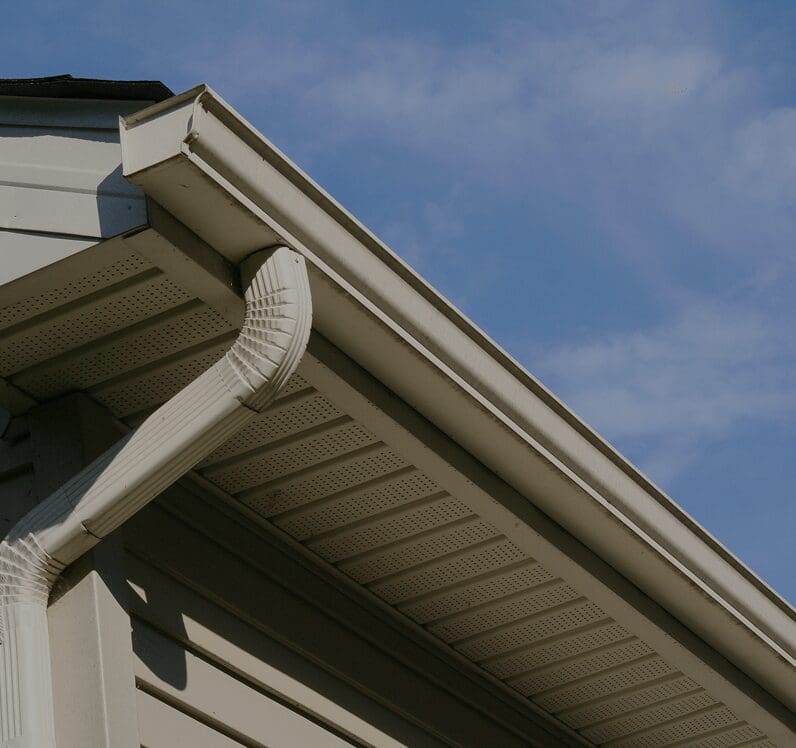 House gutter and downspout against blue sky.