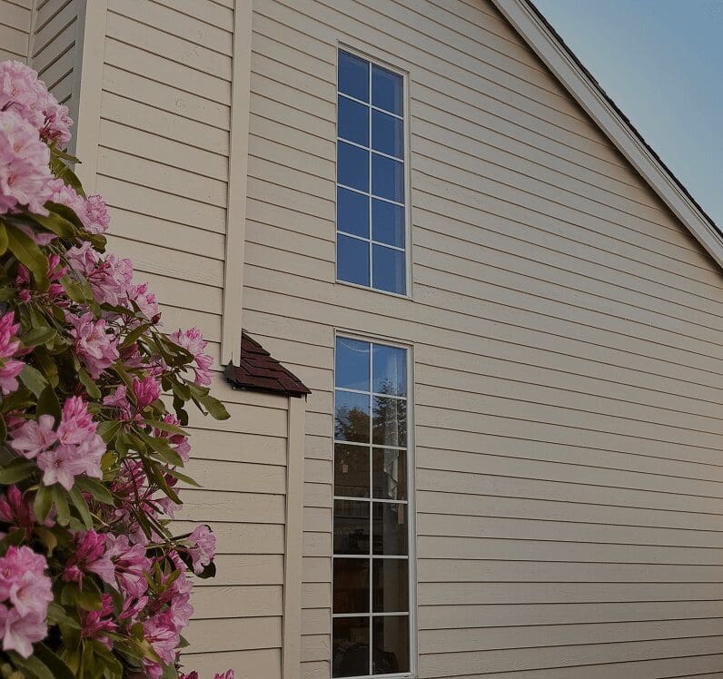 House exterior with flowers and tall windows.