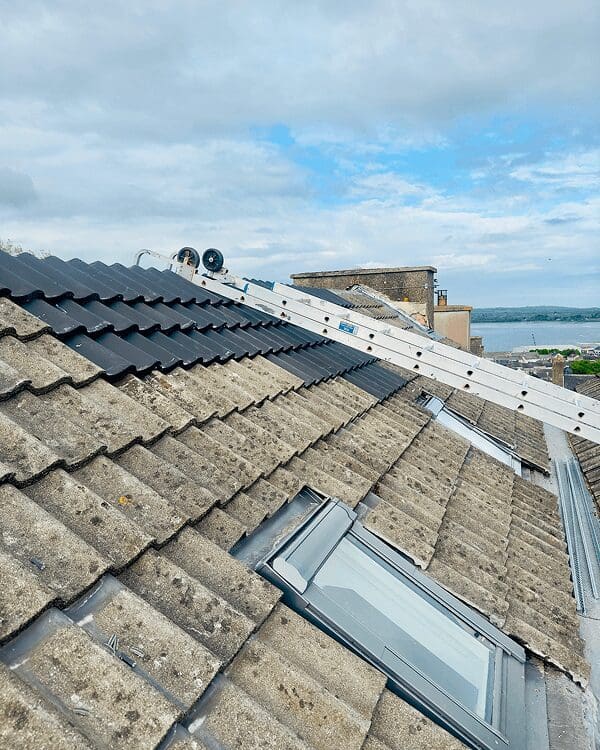 Rooftop with ladder and cloudy sky view.