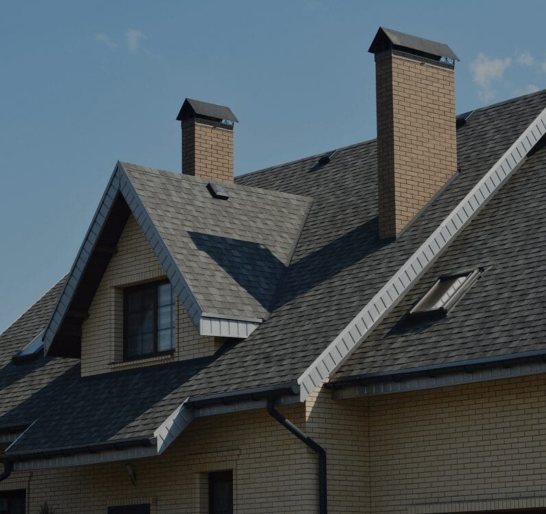 Brick house with chimneys and gabled roof.