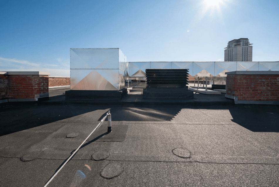 Flat rooftop with ventilation units under a bright sky.