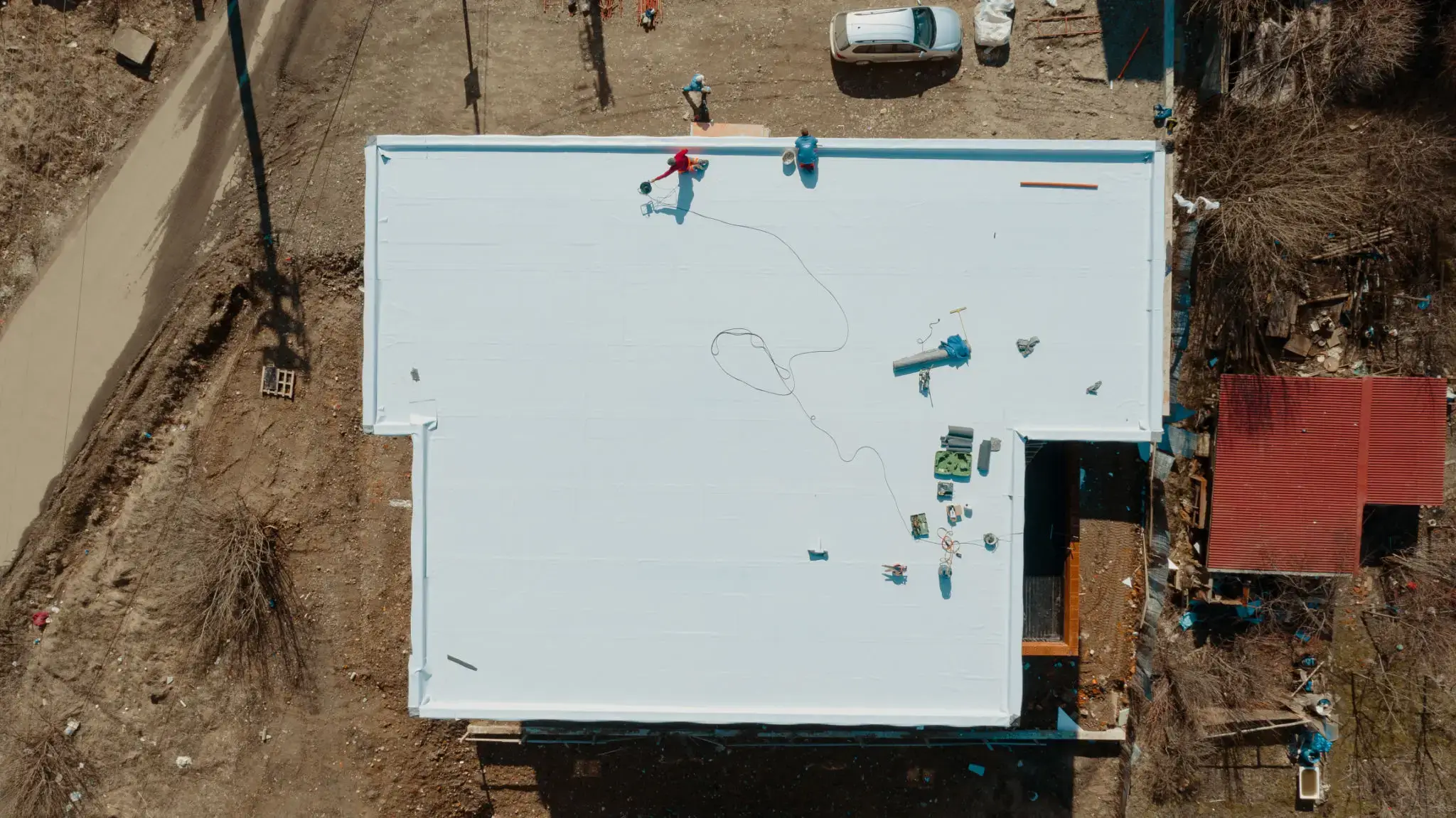 Aerial view of workers on a flat white rooftop installing equipment.