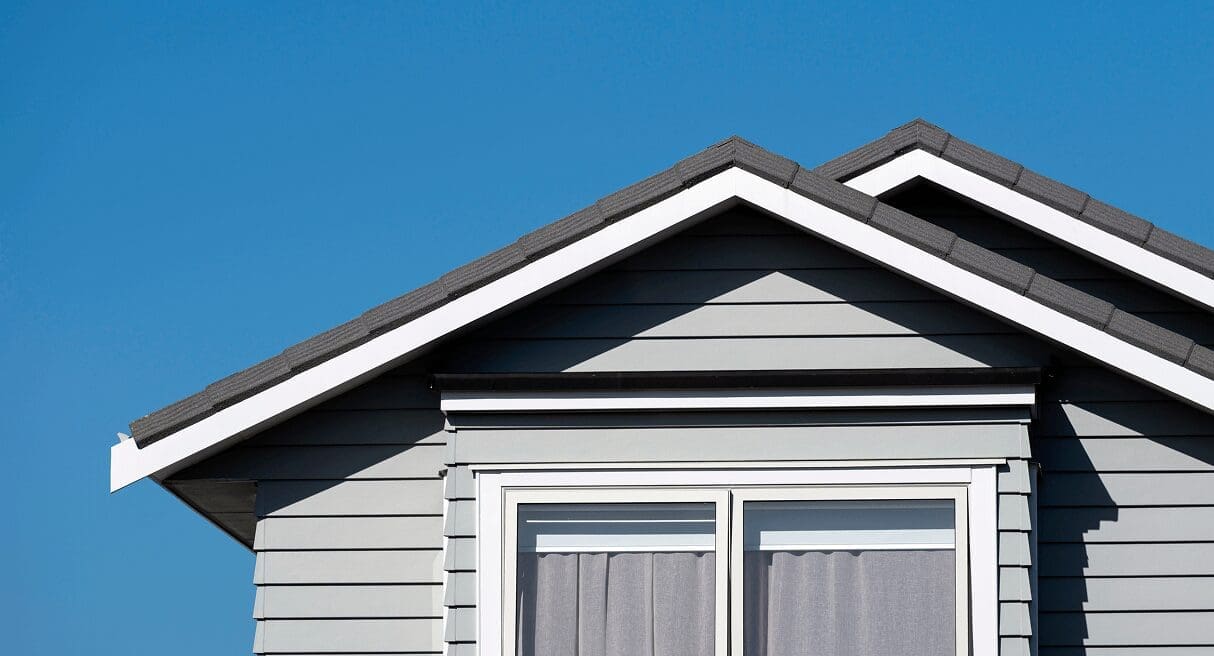 Gray house with roof against blue sky.